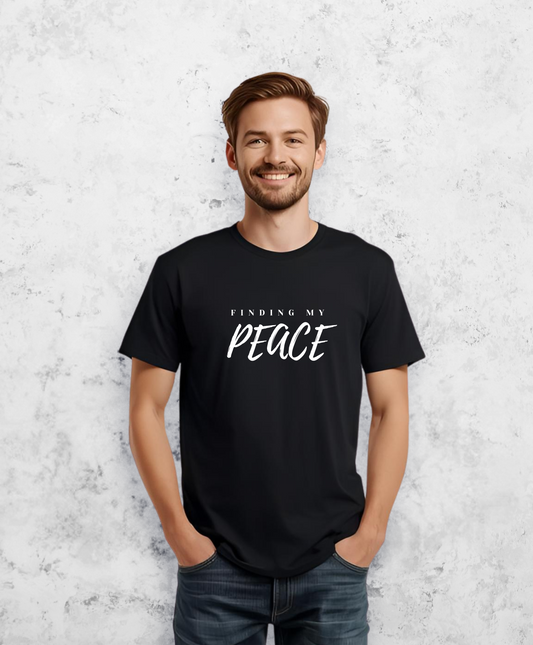 Uśmiechnięty mężczyzna, stojący przodem do kamery, ubrany w czarny t-shirt, koszulkę, z białym napisem "Finding my peace"