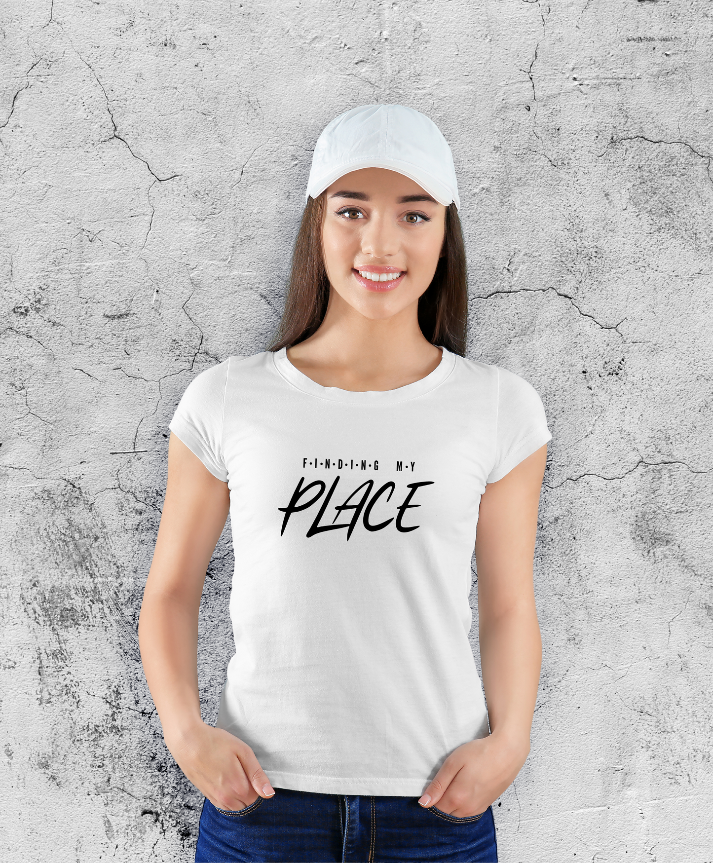 Uśmiechnięta kobieta stojąca przodem do kamery, ubrana w białą koszulki z czarnym napisem "Finding my place".