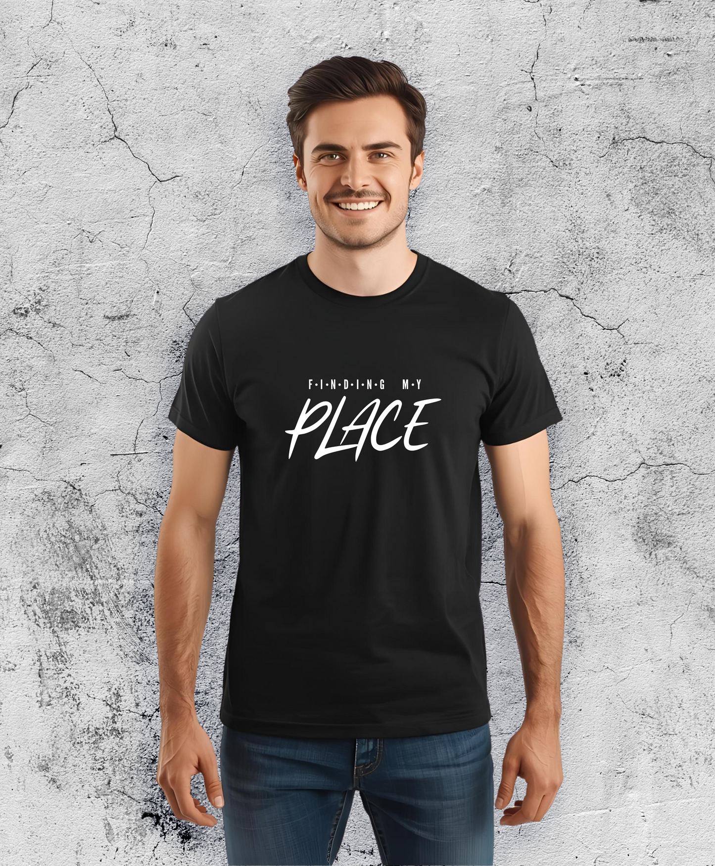 Uśmiechnięty mężczyzna stojący przodem do kamery, ubrany w czarną koszulki z białym napisem "Finding my place".