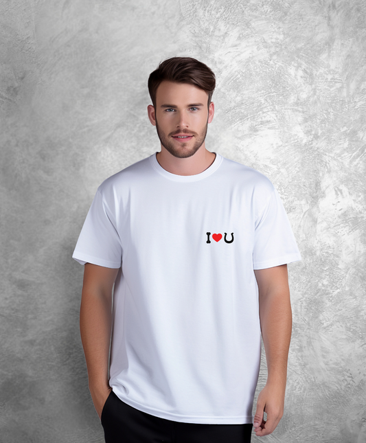 Mężczyzna stojący przodem do kamery. Ma na sobie białą koszulkę z czarnym napisem "I love horses" gdzie słowo "love" przedstawione jest jako czerwone serce, a słowo "horses" jako czarna podkowa.