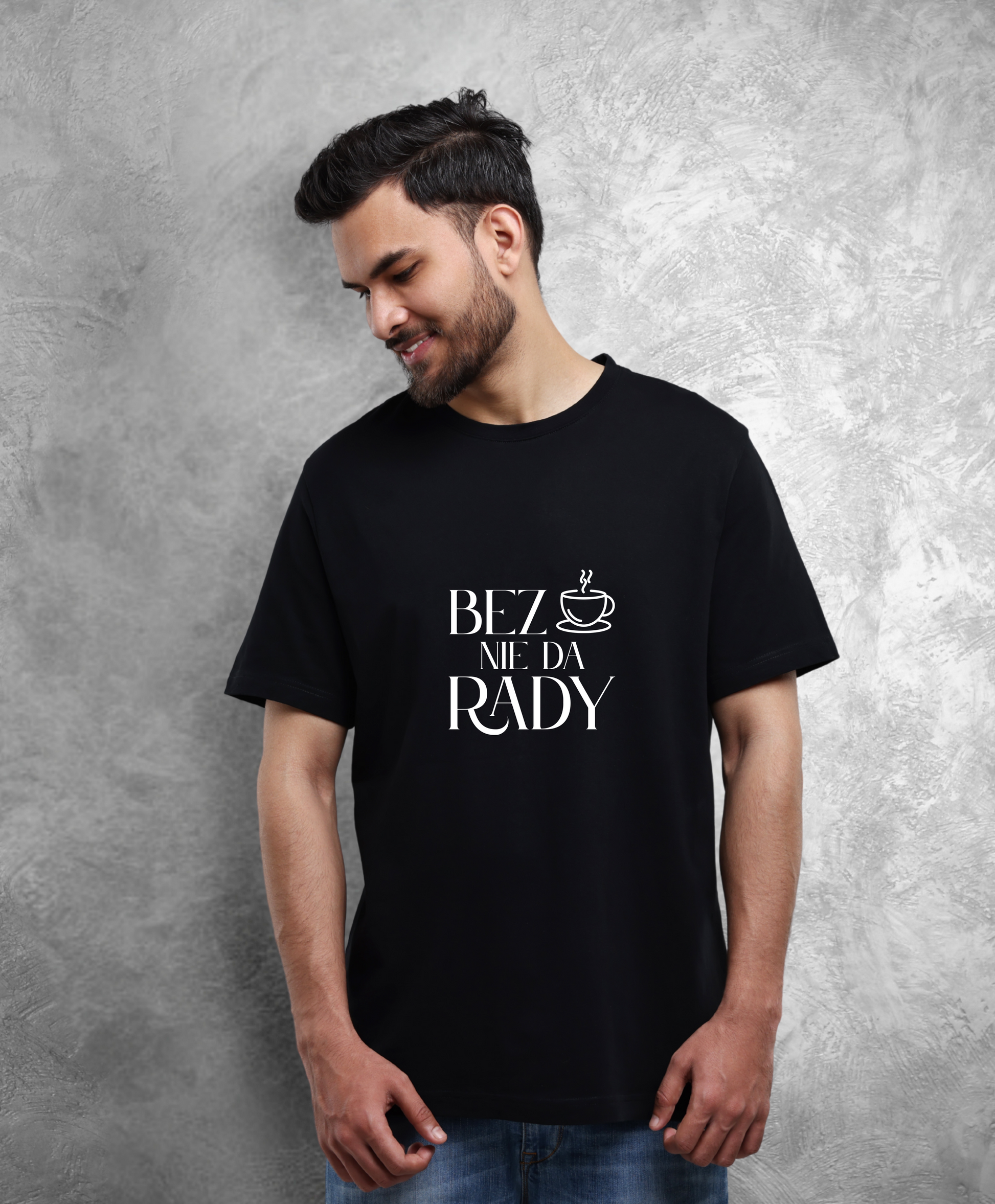 Zdjęcie przedstawia uśmiechniętego mężczyznę w czarnej koszulce z napisem "Bez kawy nie da rady". 