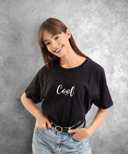 kobieta w czarnym t-shircie z białym napisem "Cool" uśmiecha się do kamery