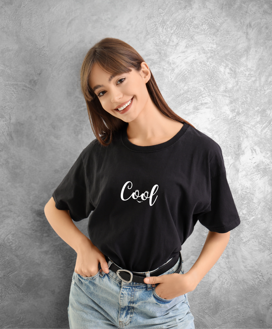 kobieta w czarnym t-shircie z białym napisem "Cool" uśmiecha się do kamery