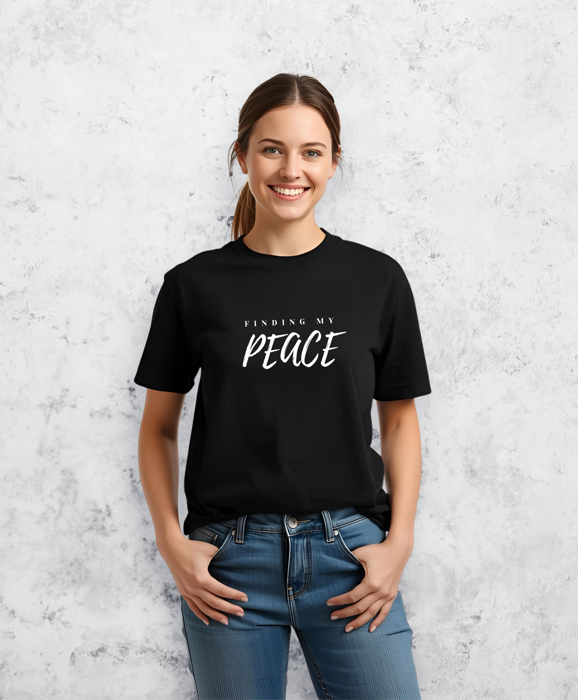 Uśmiechnięta kobieta, stojąca przodem do kamery, ubrana w czarny t-shirt, koszulkę, z białym napisem "Finding my peace"
