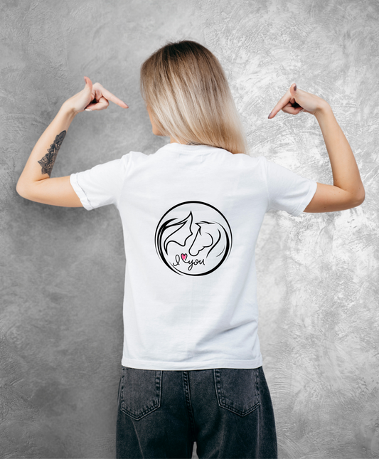 Zdjęcie przedstawia kobietę stojącą tyłem do kamery. Ubrana jest w biały t-shirt z nadrukiem na plecach.  Nadruk przedstawia koło z graficznie pokazaną głową kobiety i konia z profilu oraz napis I love you, gdzie słowo "love" przedstawione jest jako różowe serce. Reszta nadruku jest w kolorze czarnym.