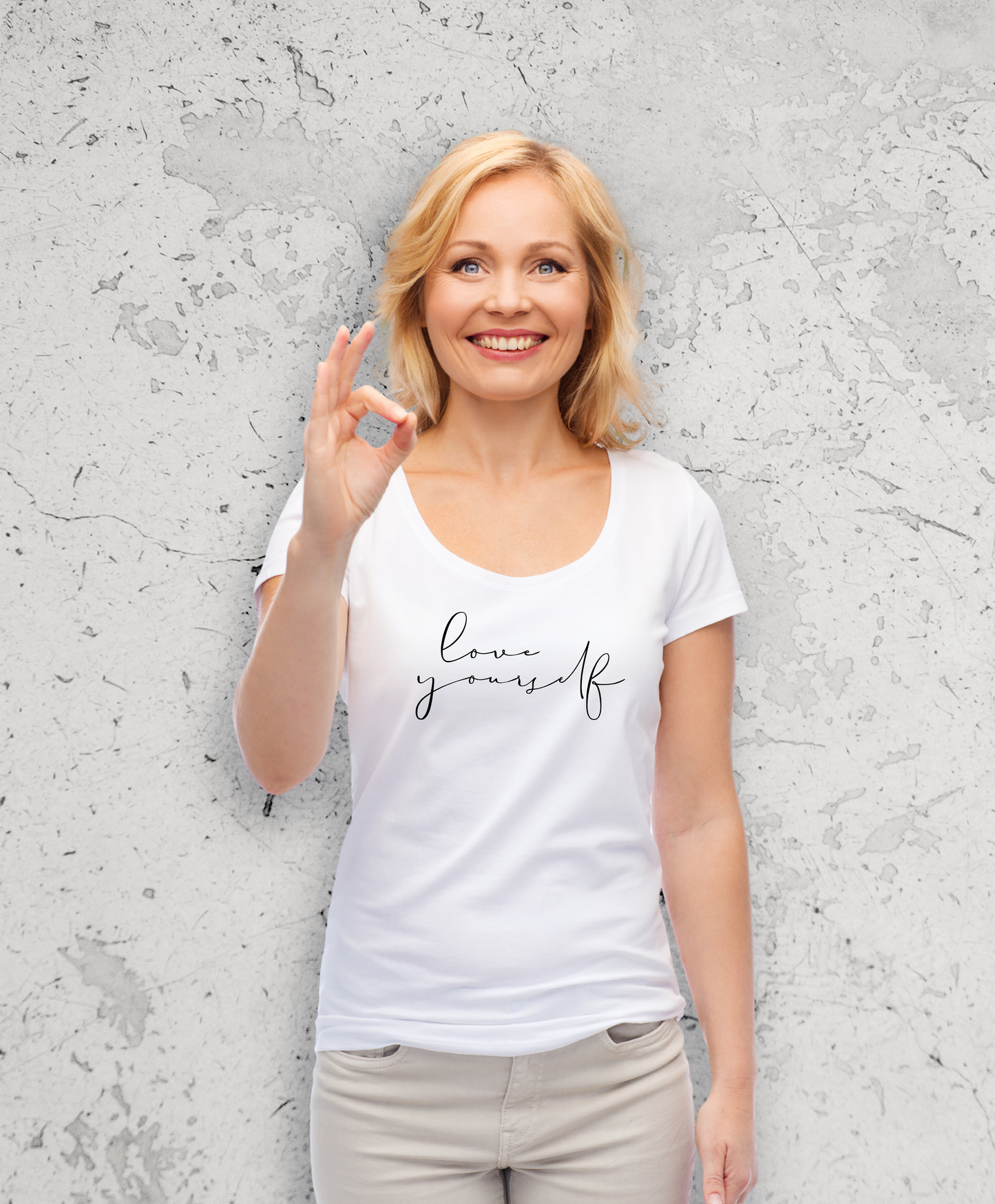 Uśmiechnięta kobieta w białym t-shirta z czarnym nadrukiem "Love yourself"