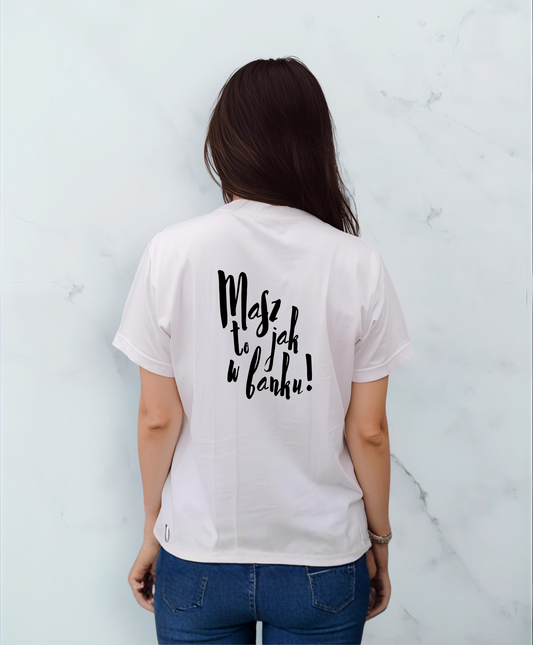 Kobieta stojąca tyłem do kamery. Ubrana w białą koszulkę z czarnym napisem "Masz to jak w banku" na plecach