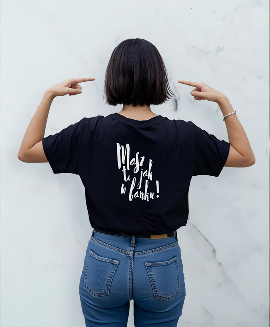 Kobieta stojąca tyłem do kamery. Ubrana w czarną koszulkę z białym napisem "Masz to jak w banku" na plecach