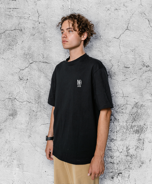 Mężczyzna w czarnym t-shircie z biały małym białym napisem "No drama"