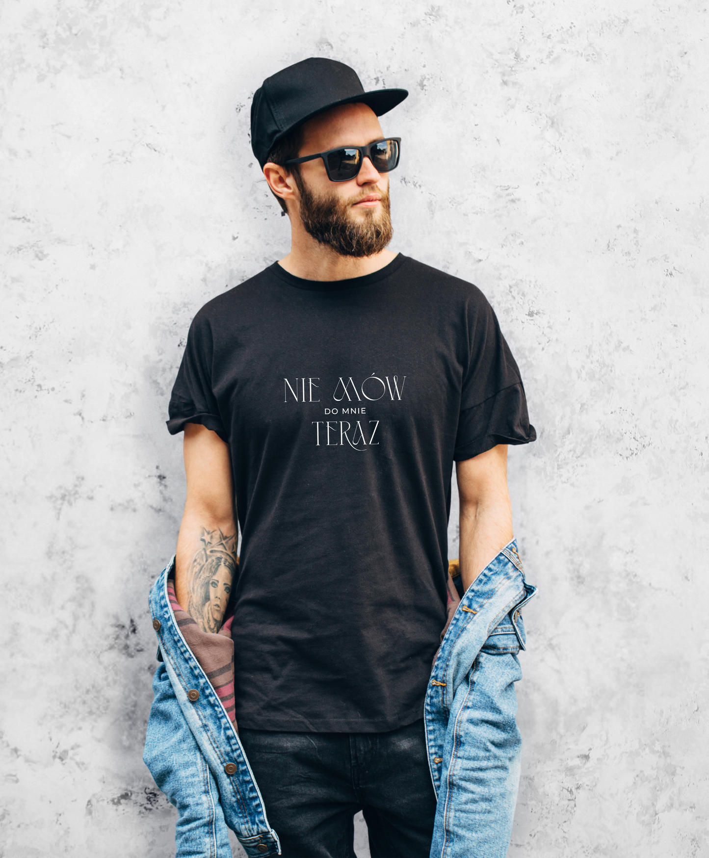 Zdjęcie przedstawia mężczyznę w czarnej koszulce z białym napisem "Nie mów do mnie teraz". 
