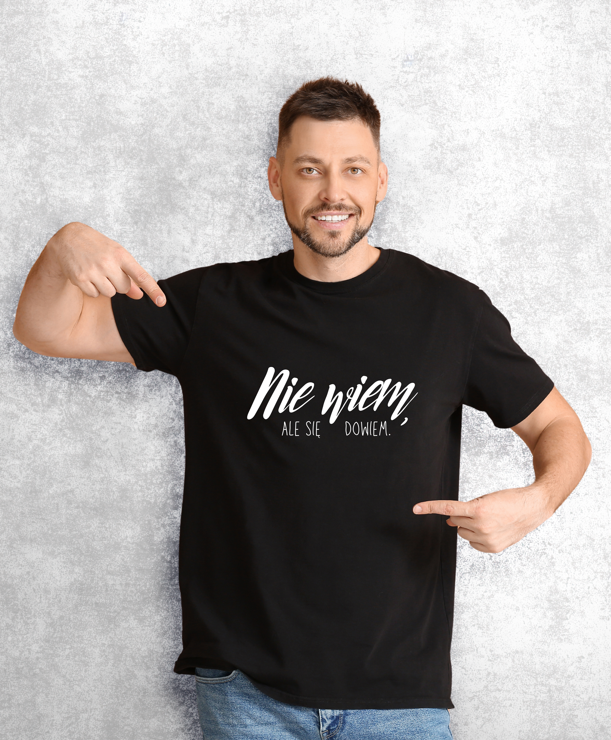 Uśmiechnięty mężczyzna w czarnym t-shircie z białym napisem "Nie wiem, ale się dowiem"