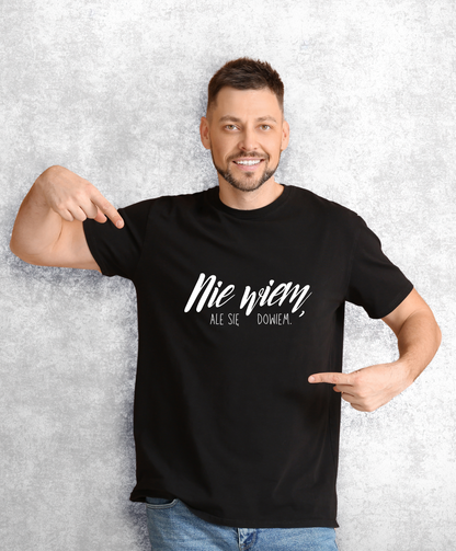 Uśmiechnięty mężczyzna w czarnym t-shircie z białym napisem "Nie wiem, ale się dowiem"
