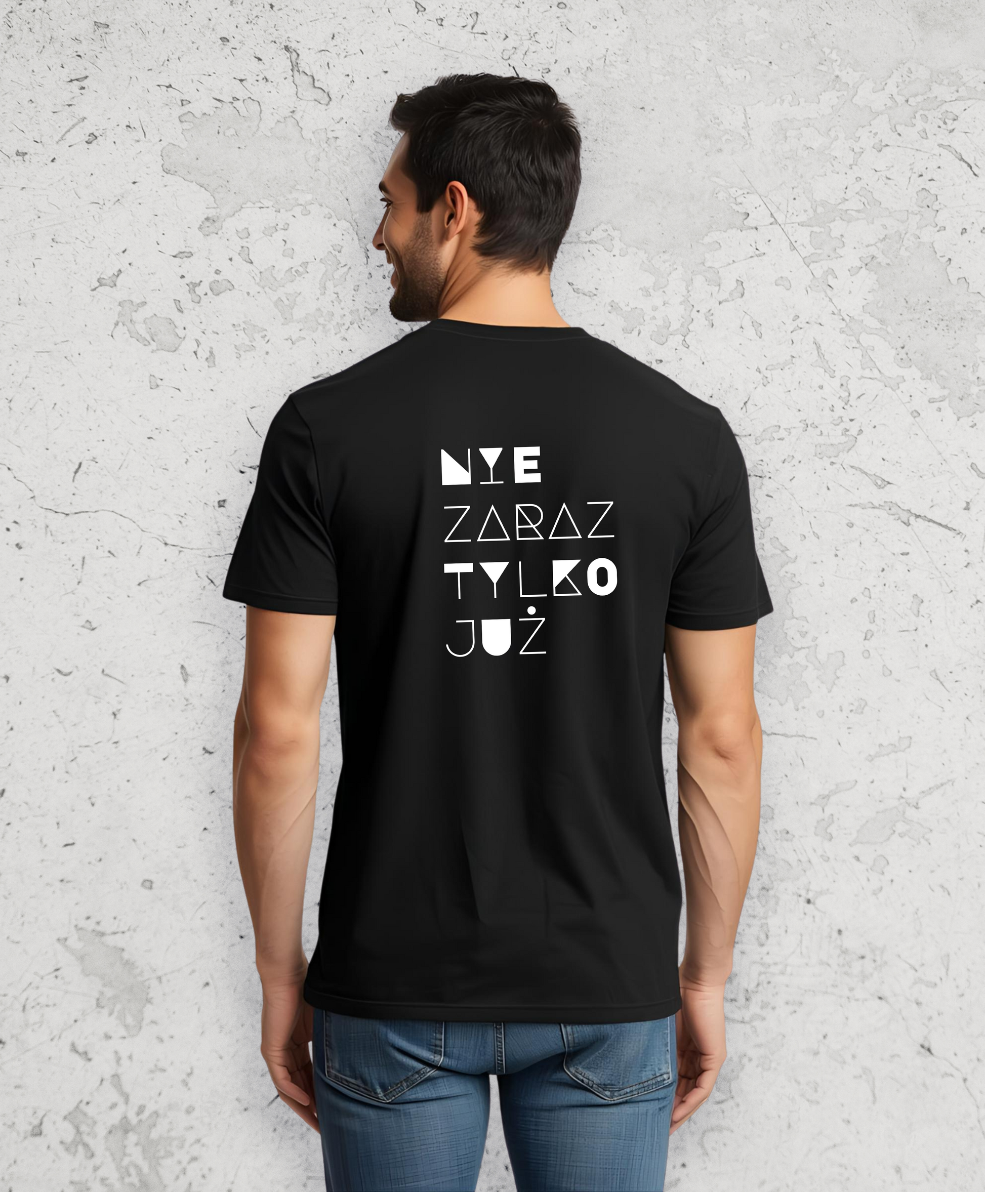 Mężczyzna stojący tyłem do kamery. Ubrany w czarny t-shirt z białym napisem na plecach "Nie zaraz, tylko już"