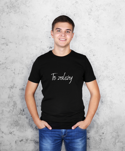 Zdjęcie przedstawia uśmiechniętego mężczyznę, stojącego przodem do kamery, ubranego w czarną koszulkę z białym napisem na przodzie "To zależy"