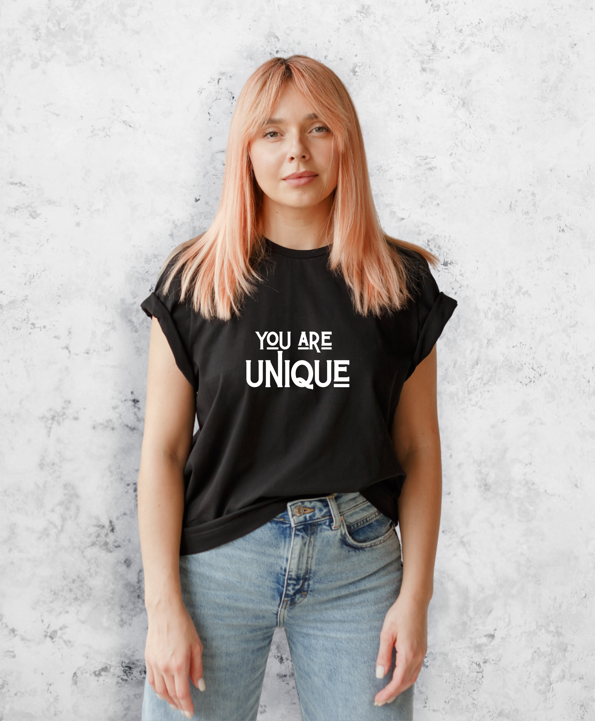 Zdjęcie przedstawia kobietę w czarnej koszulce z białym napisem "You are unique".