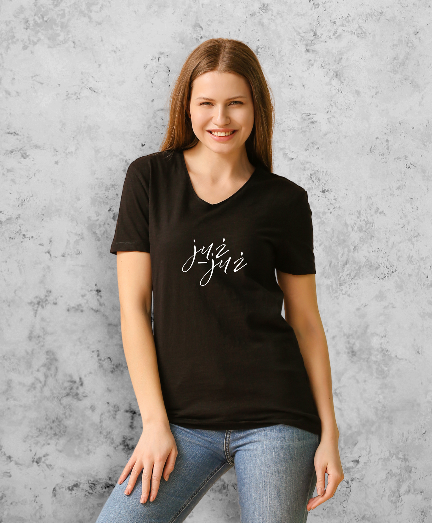 Uśmiechnięta kobieta stojąca przodem do kamery, ubrana w czarną koszulkę z białym napisem "już już"