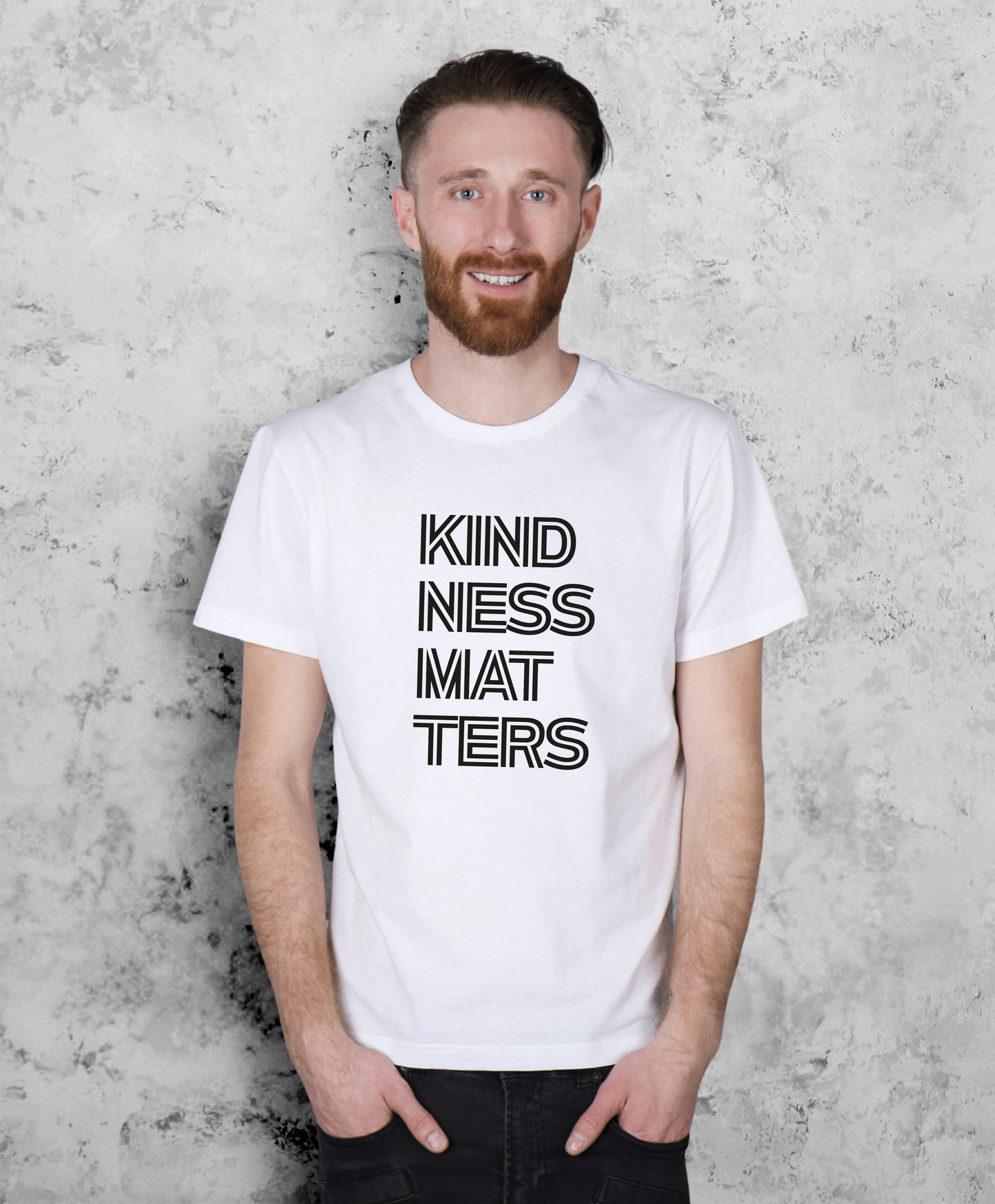 Mężczyzna stojący przodem do kamery. Ma na sobie białą koszulkę z czarnym napisem "Kindness matters"