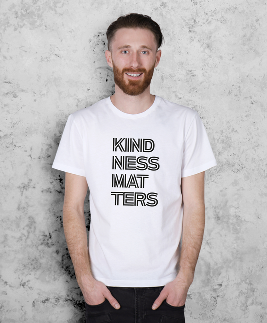 Mężczyzna stojący przodem do kamery. Ma na sobie białą koszulkę z czarnym napisem "Kindness matters"